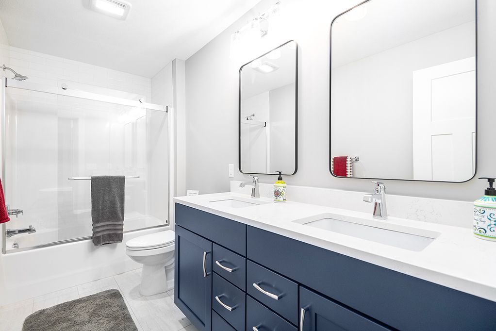 A bathroom with two sinks , a toilet , and a walk in shower.