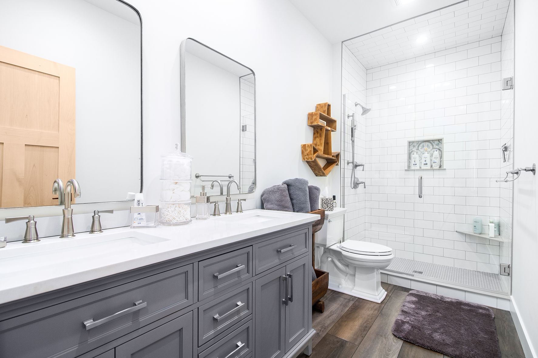A bathroom with two sinks , a toilet , and a walk in shower.