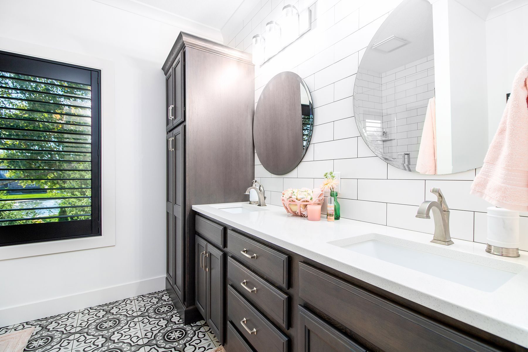 A bathroom with two sinks , two mirrors and a window.