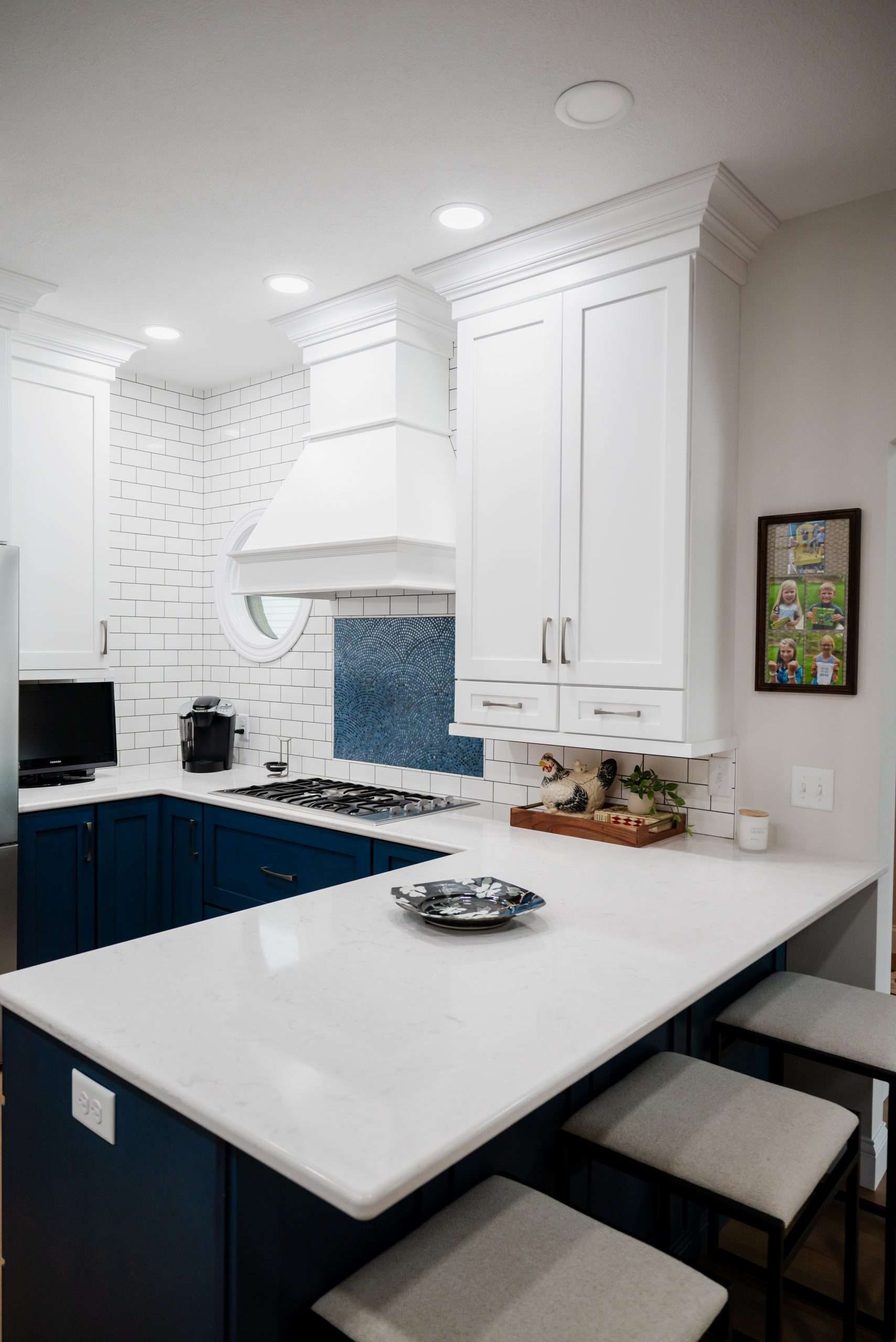 A kitchen with white cabinets and blue cabinets and a white counter top.