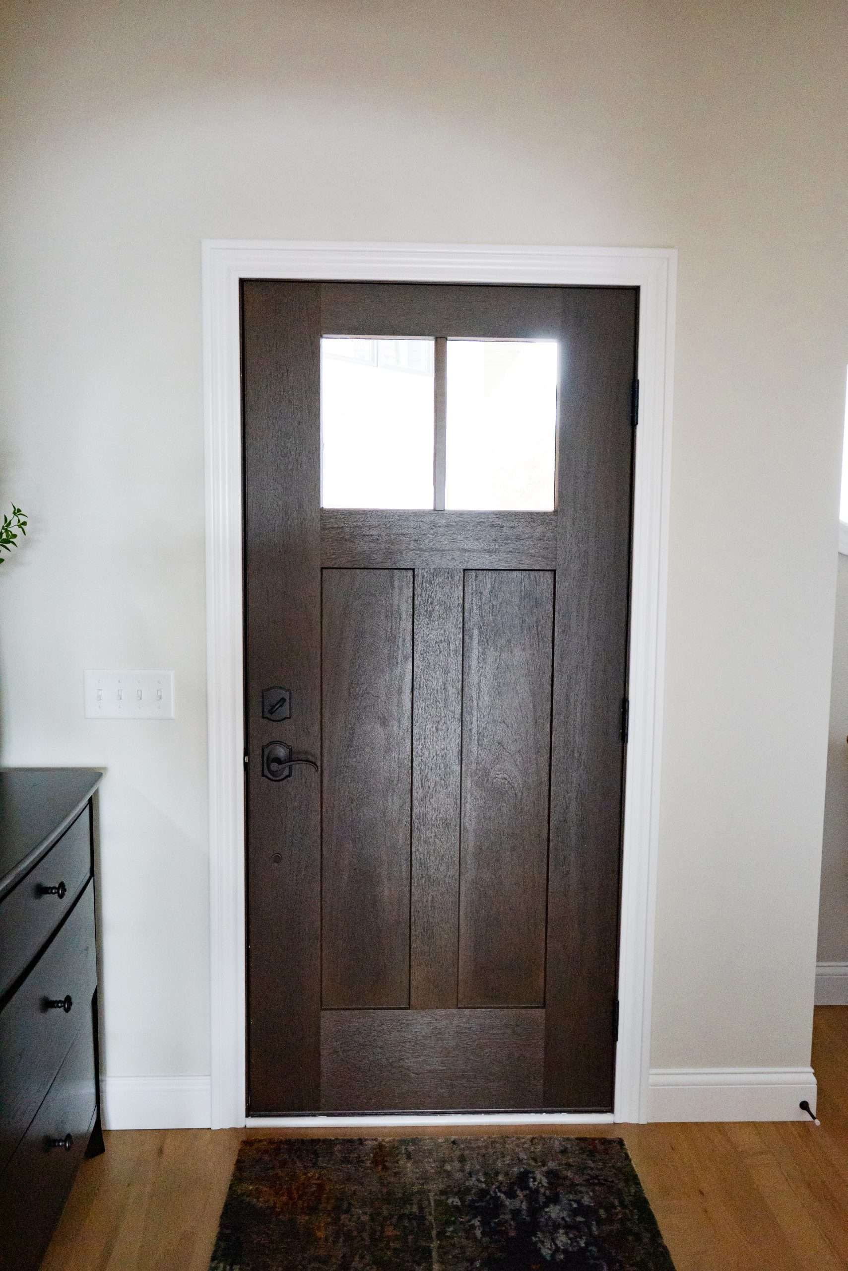 A brown door with a small window in a hallway.