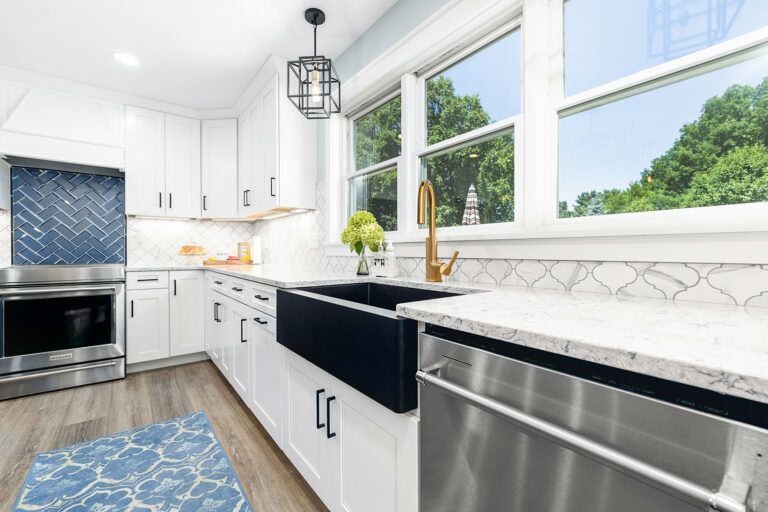 A kitchen with green cabinets , white counter tops , and stainless steel appliances.