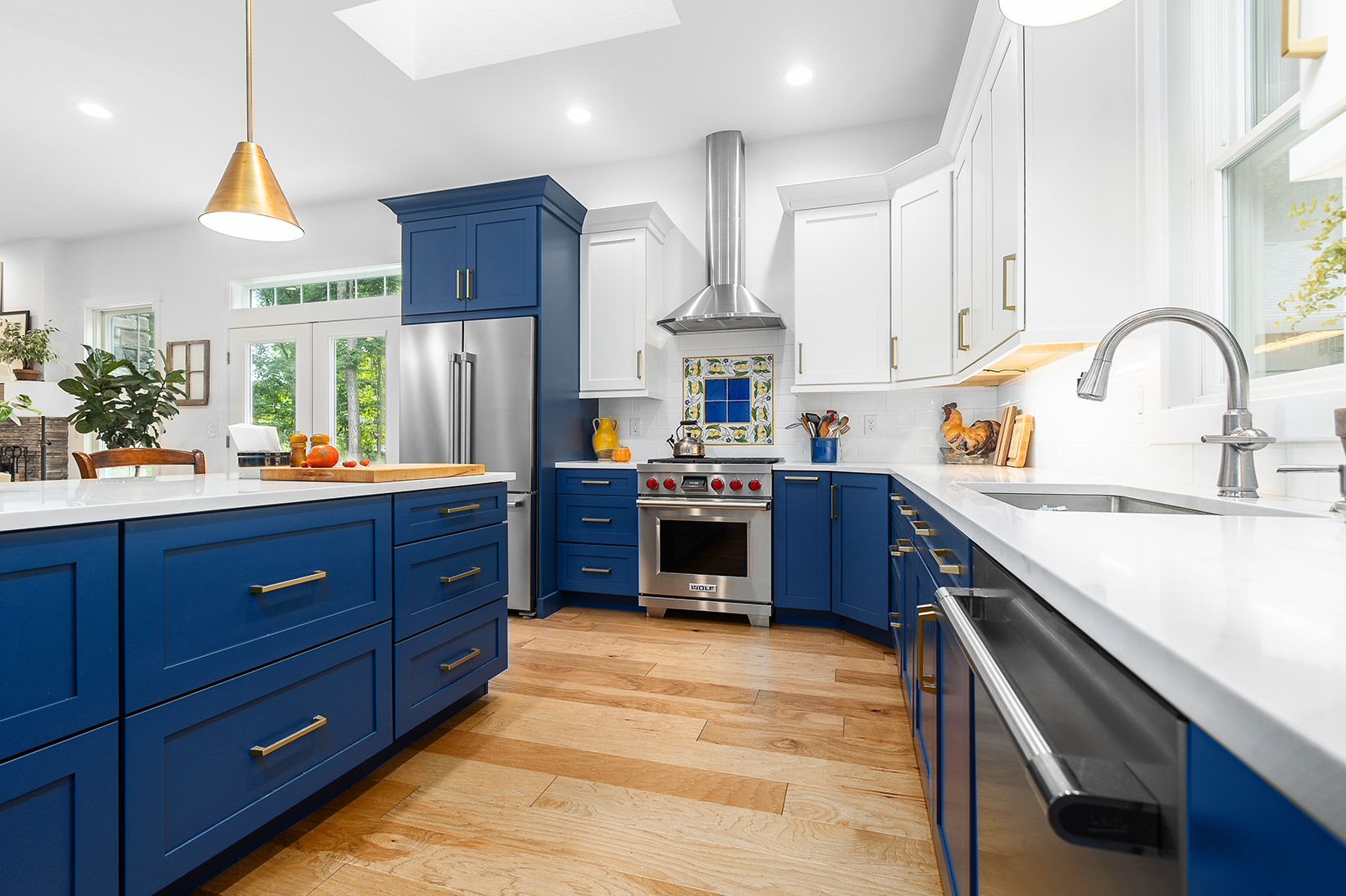 A kitchen with blue cabinets , white cabinets , and stainless steel appliances.