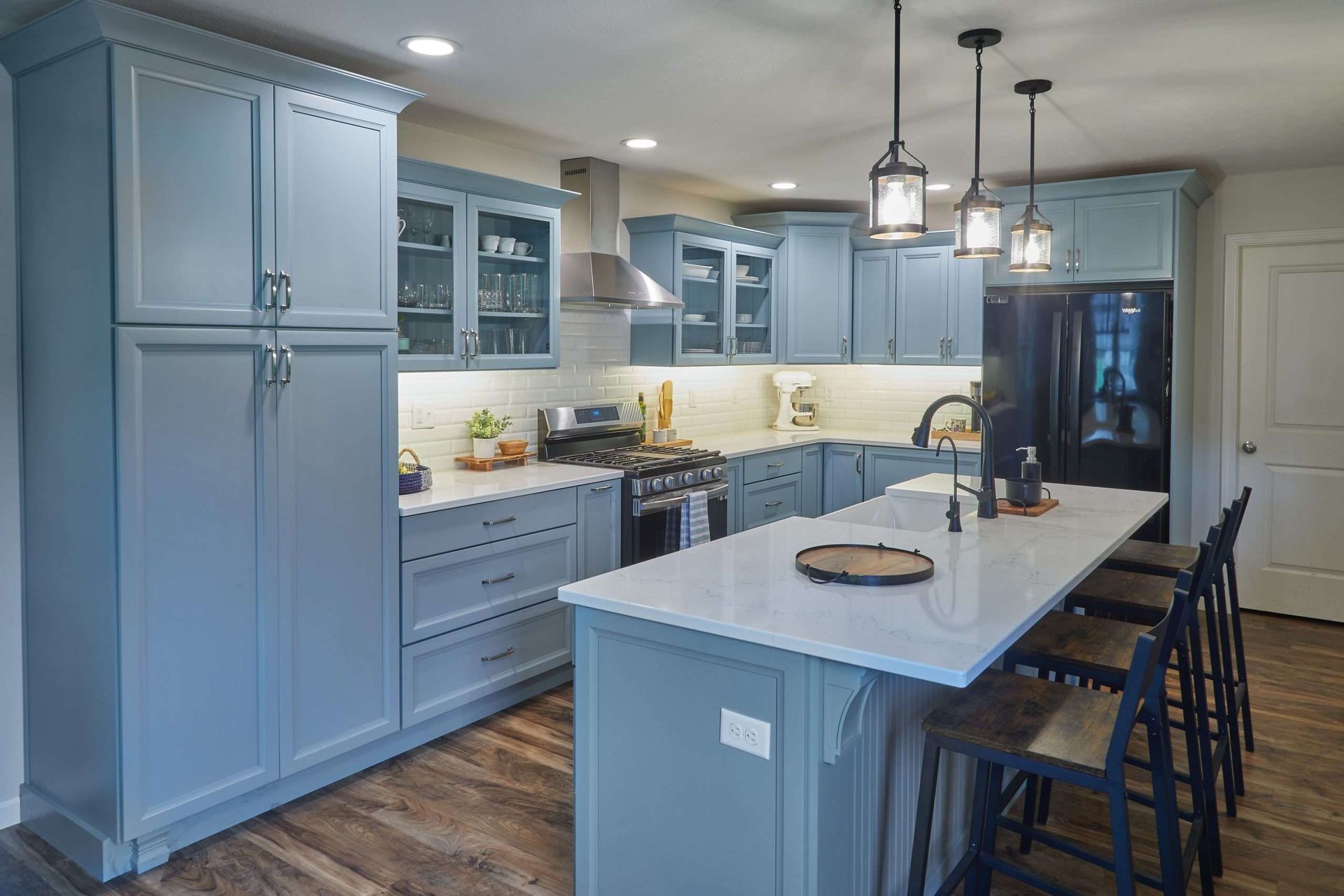 A bathroom with two sinks , two mirrors , and blue cabinets.