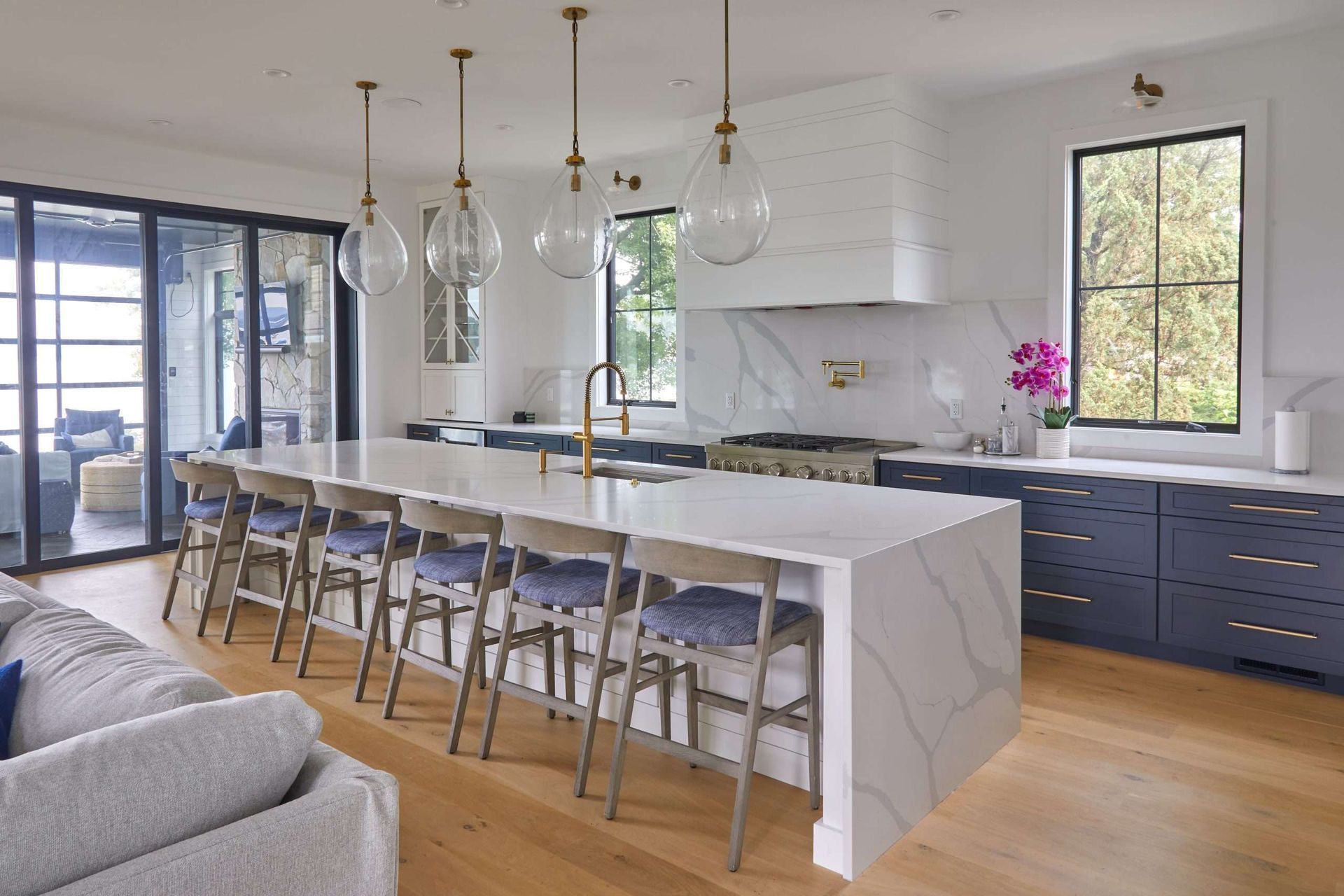 A kitchen with a large island and stools in a living room.