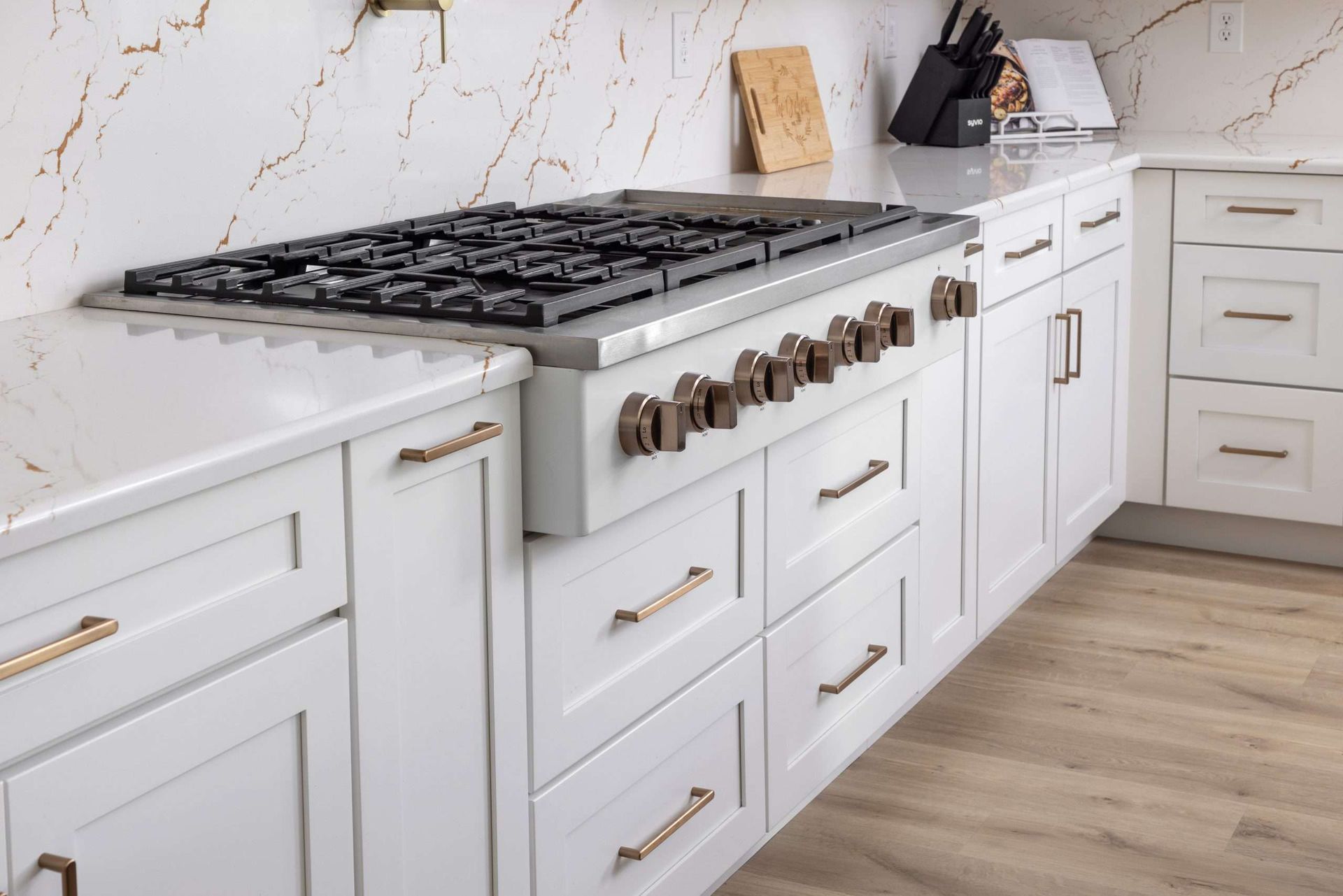A kitchen with white cabinets and a stove top oven.
