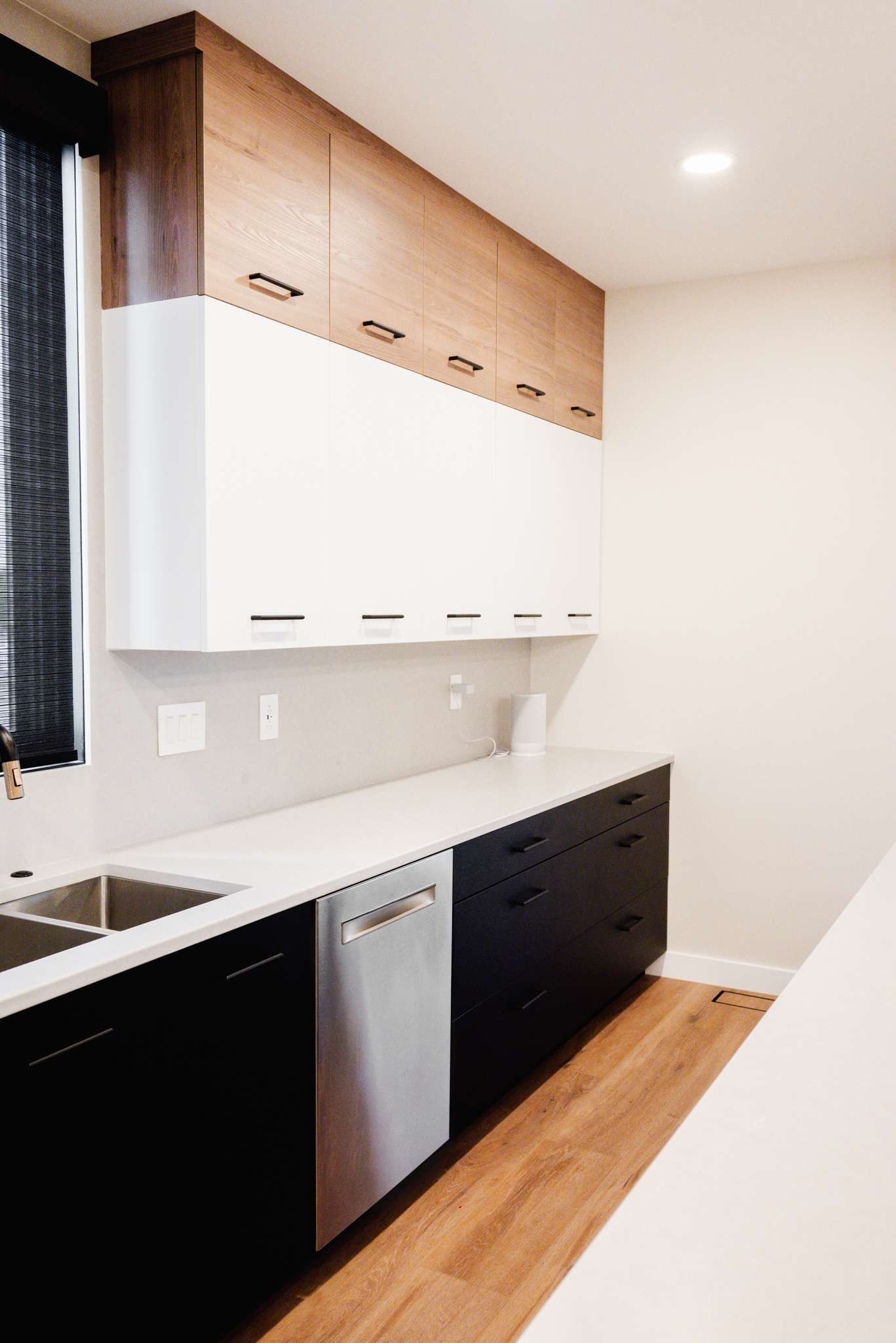 A kitchen with black and white cabinets and a stainless steel dishwasher.