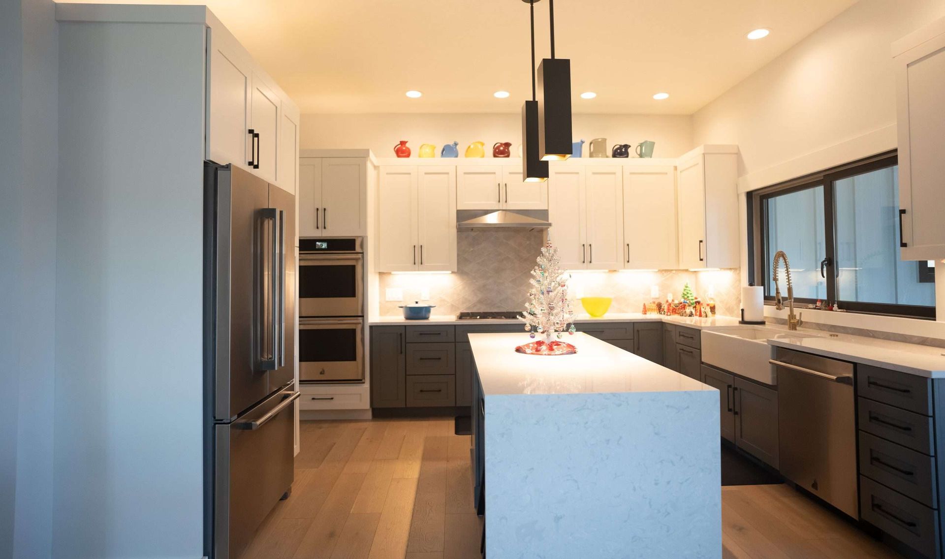 A kitchen with black cabinets , white counter tops , stainless steel appliances and a large island.