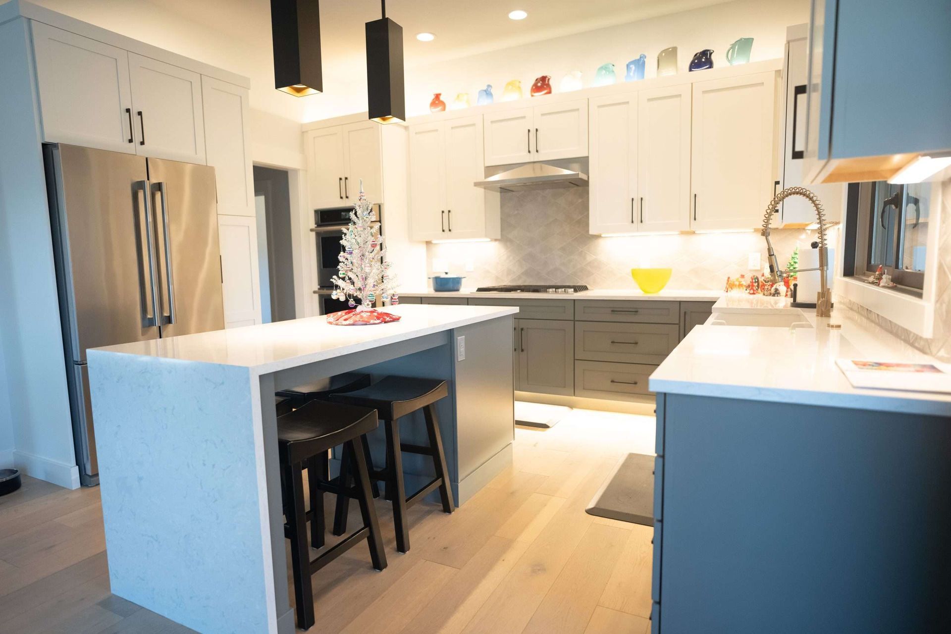A kitchen with a large island and stools and a christmas tree on the counter.
