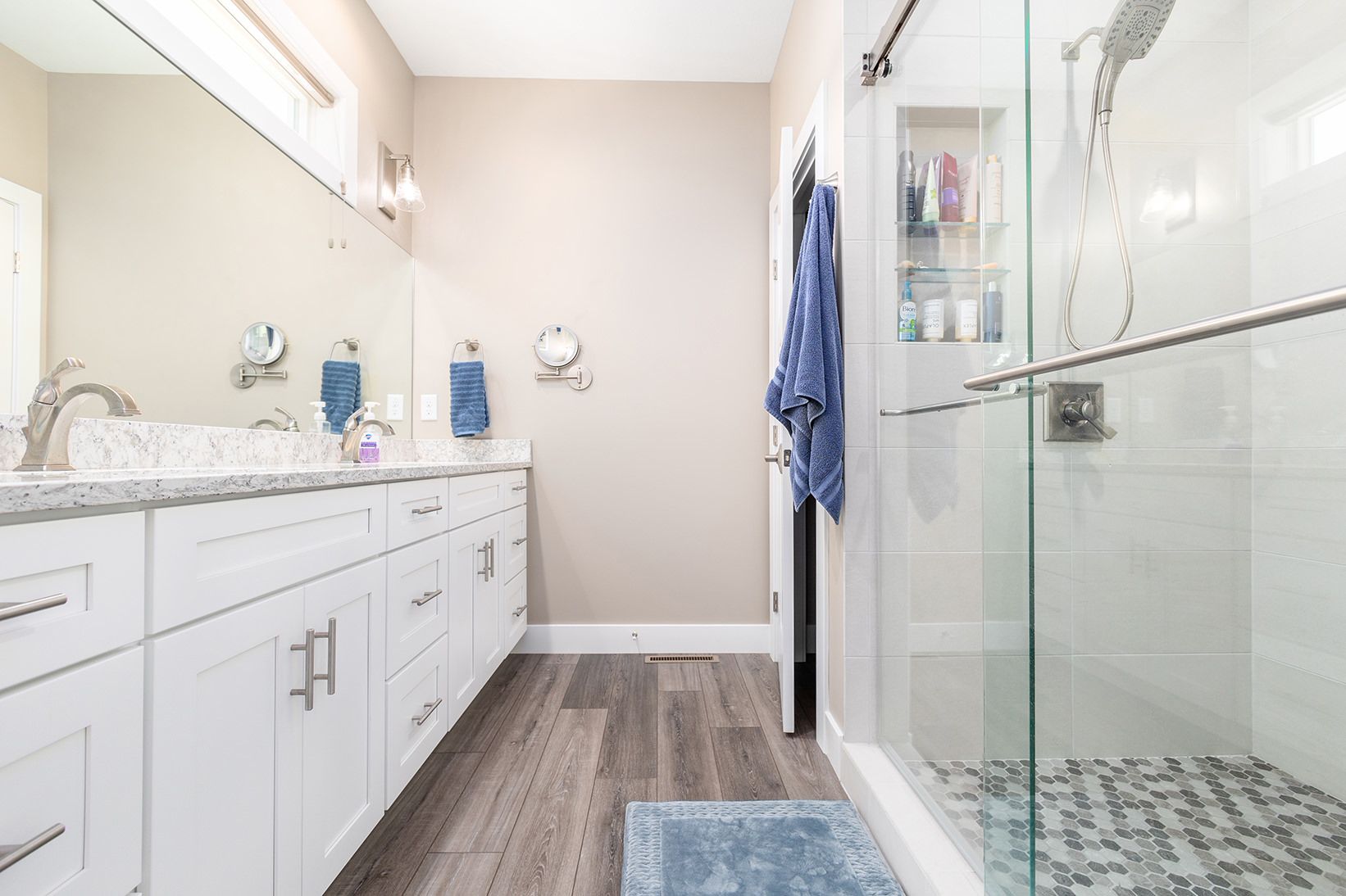 A bathroom with two sinks and a walk in shower.