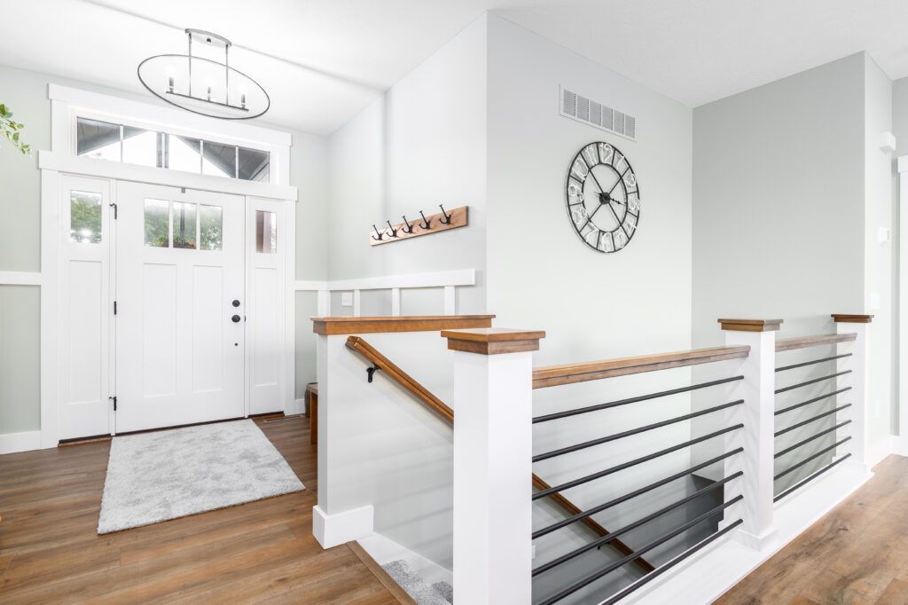 There is a clock on the wall above the stairs in the hallway.