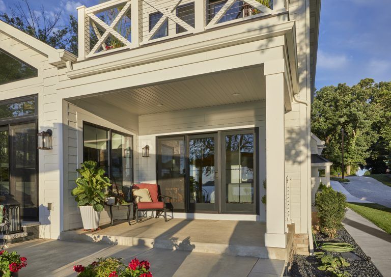 A white house with a large porch and sliding glass doors.