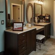 A bathroom with two sinks , two mirrors , a vanity , and a stool.