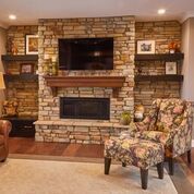 A living room with a brick fireplace , television , chair and ottoman.