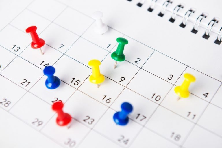 A calendar with a bunch of pins on it