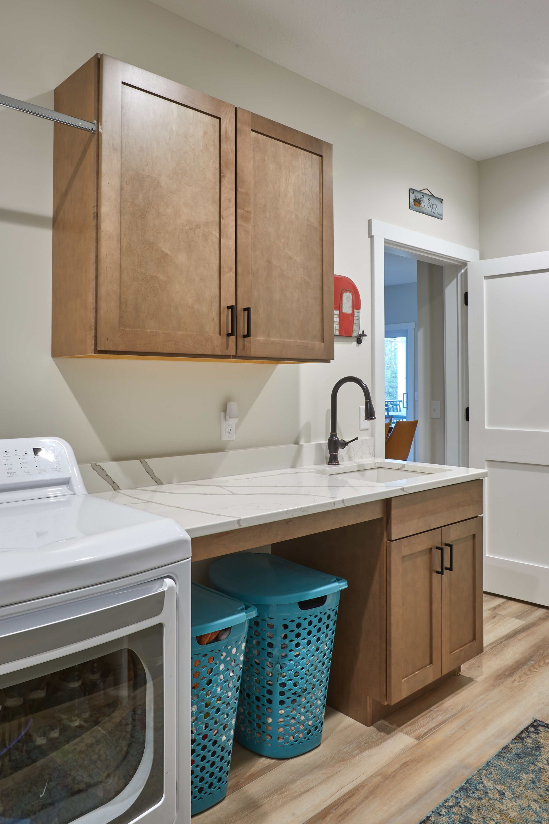 Modern kitchen with white and wood cabinets, marble countertops, and stainless steel appliances.