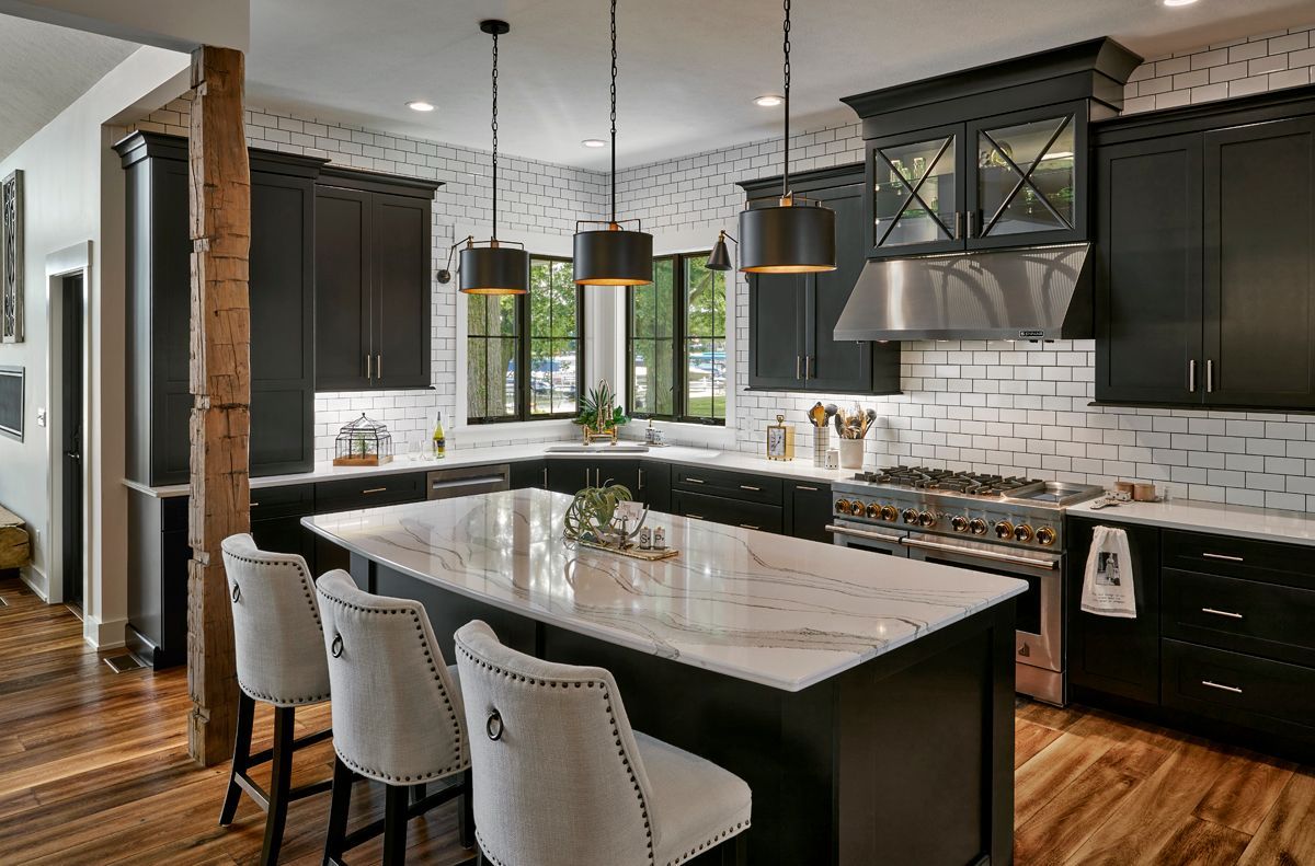 A kitchen with black cabinets , white counter tops , stainless steel appliances and a large island.