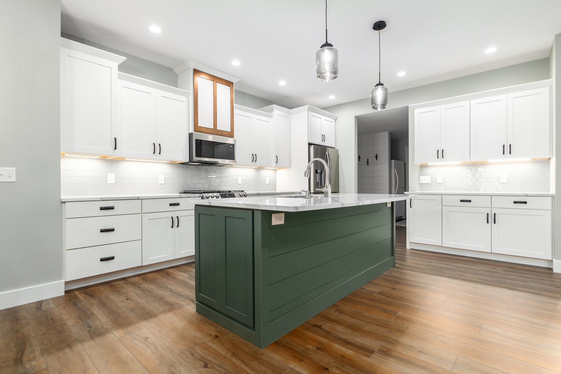 A kitchen with white cabinets and a green island.