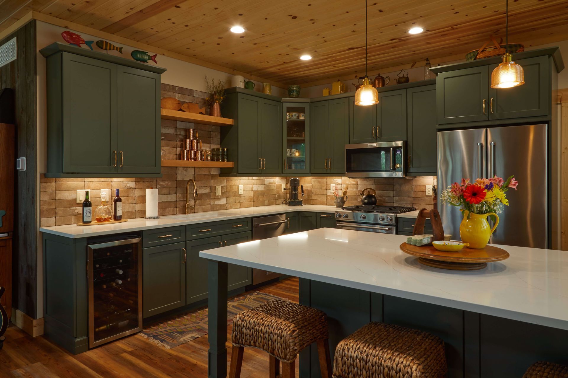 Green kitchen with white countertops, stainless steel appliances, and a wooden ceiling.