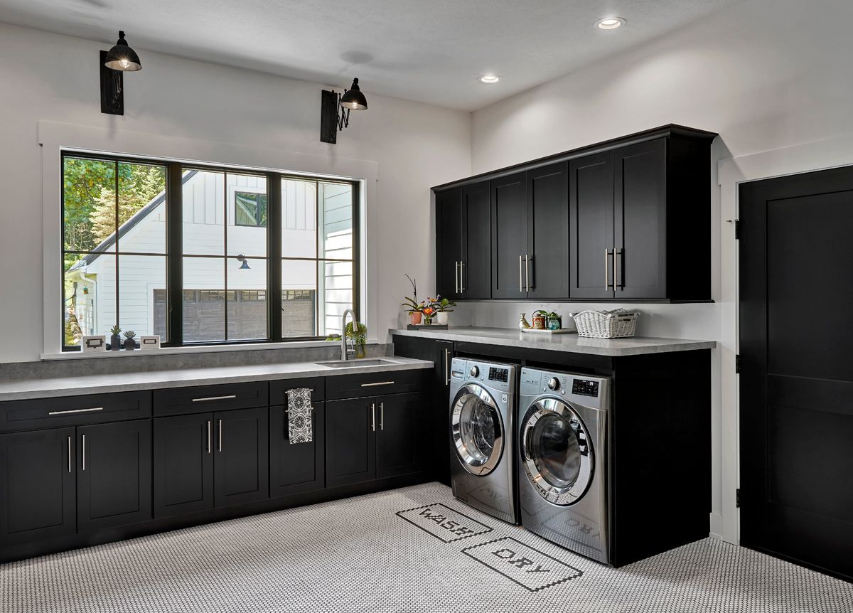 A laundry room with black cabinets and stainless steel appliances.