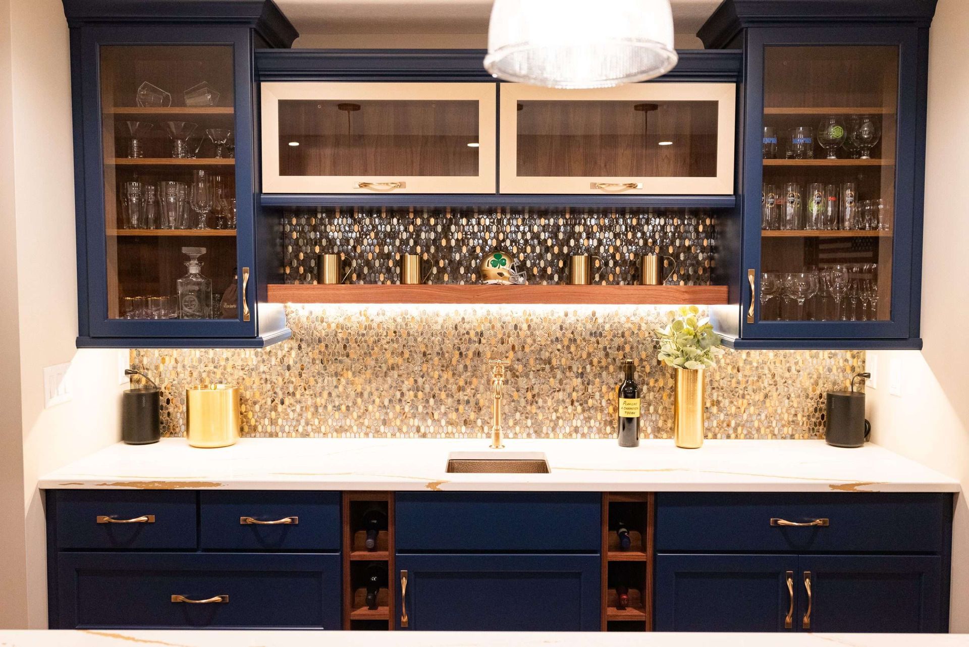 A kitchen with blue cabinets , white counter tops , a sink , and a wine rack.