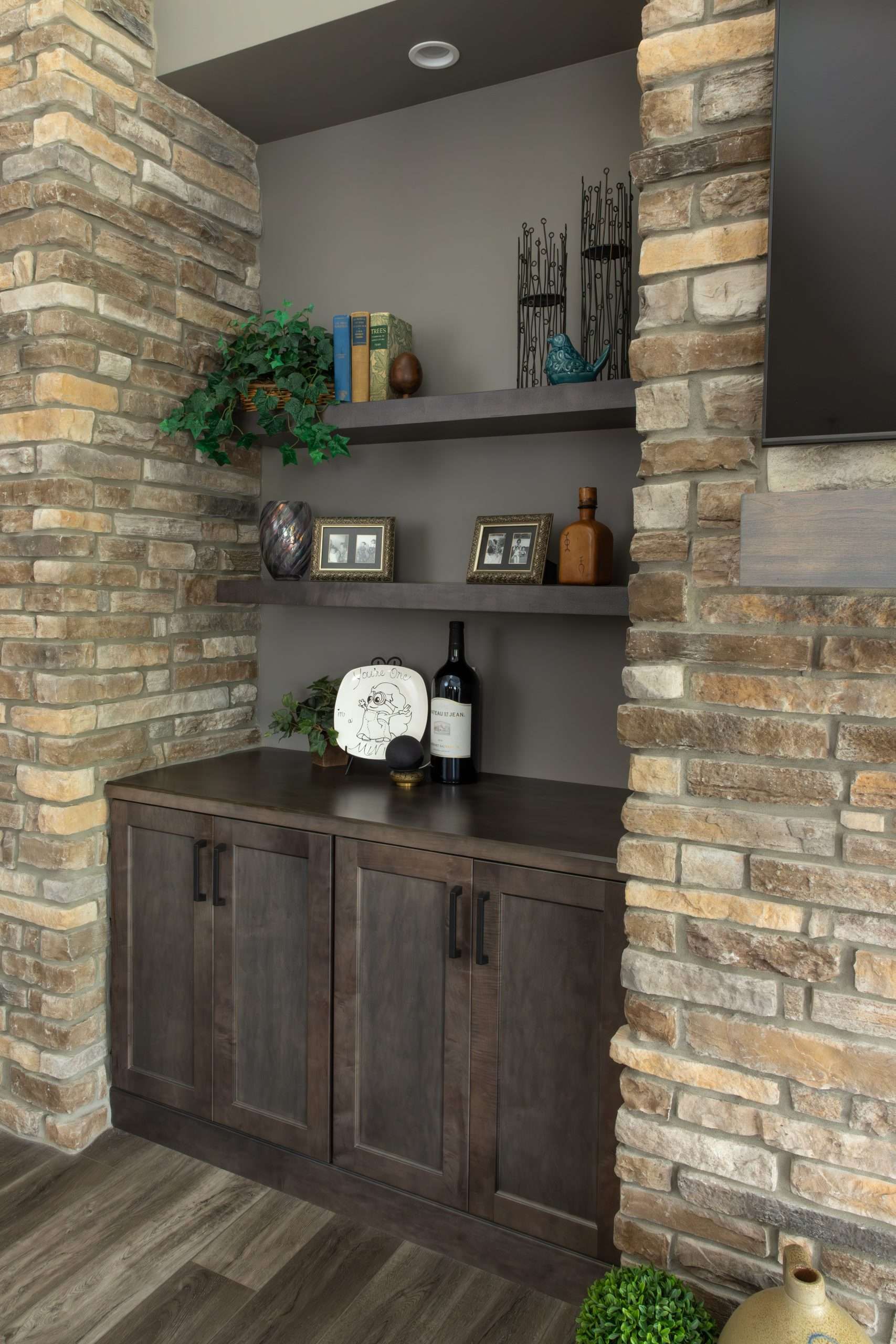 A shelf with a bottle of wine on it in a room with a brick wall.