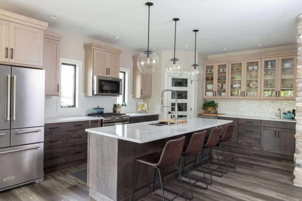 A kitchen with a large island and stools in a living room.
