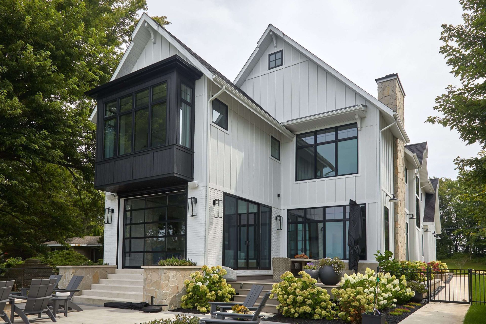 A large white house with black windows and a patio in front of it.