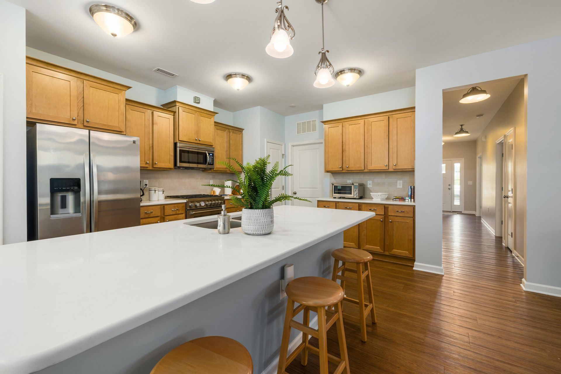 A kitchen with wooden cabinets , stainless steel appliances , a large island and stools.