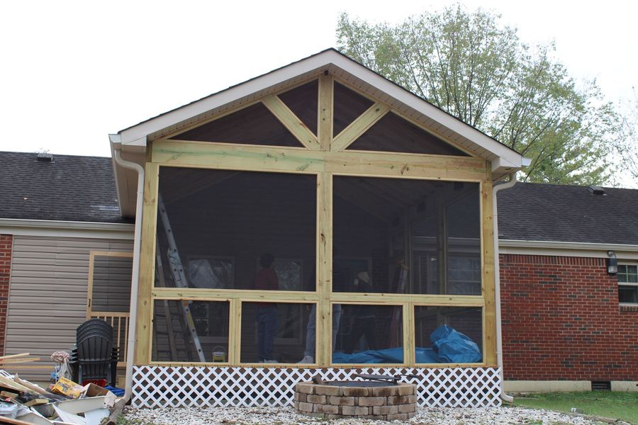 Screened-in porch addition with wood framing, attached to a brick home. Includes screens, lattice, and a gable roof.