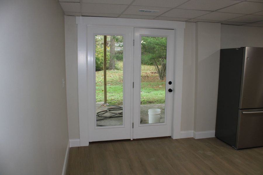 White French doors leading to a backyard. A refrigerator sits to the right of the doors.