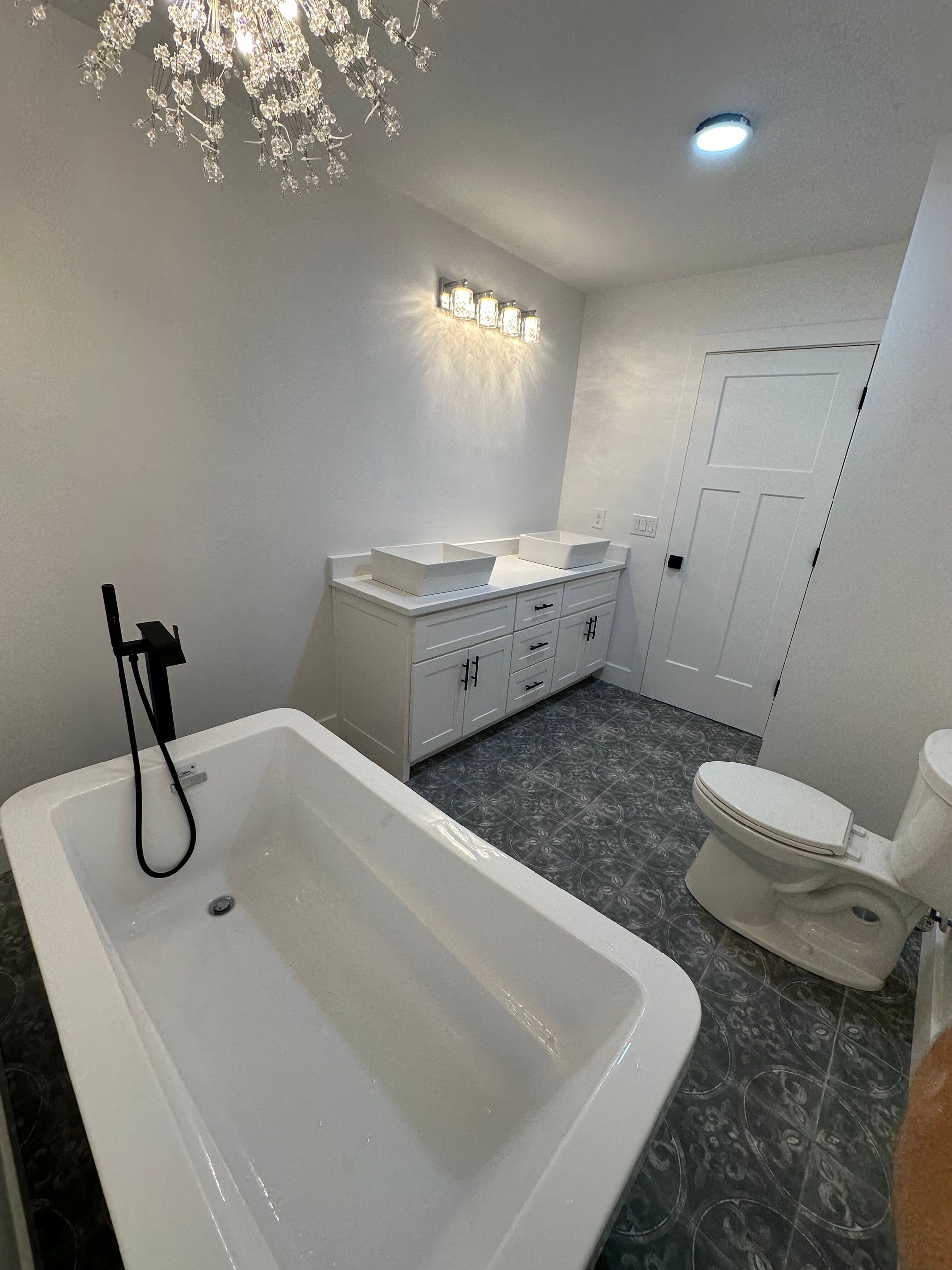 White bathroom vanity with marble countertop, round backlit mirror, and silver faucet.