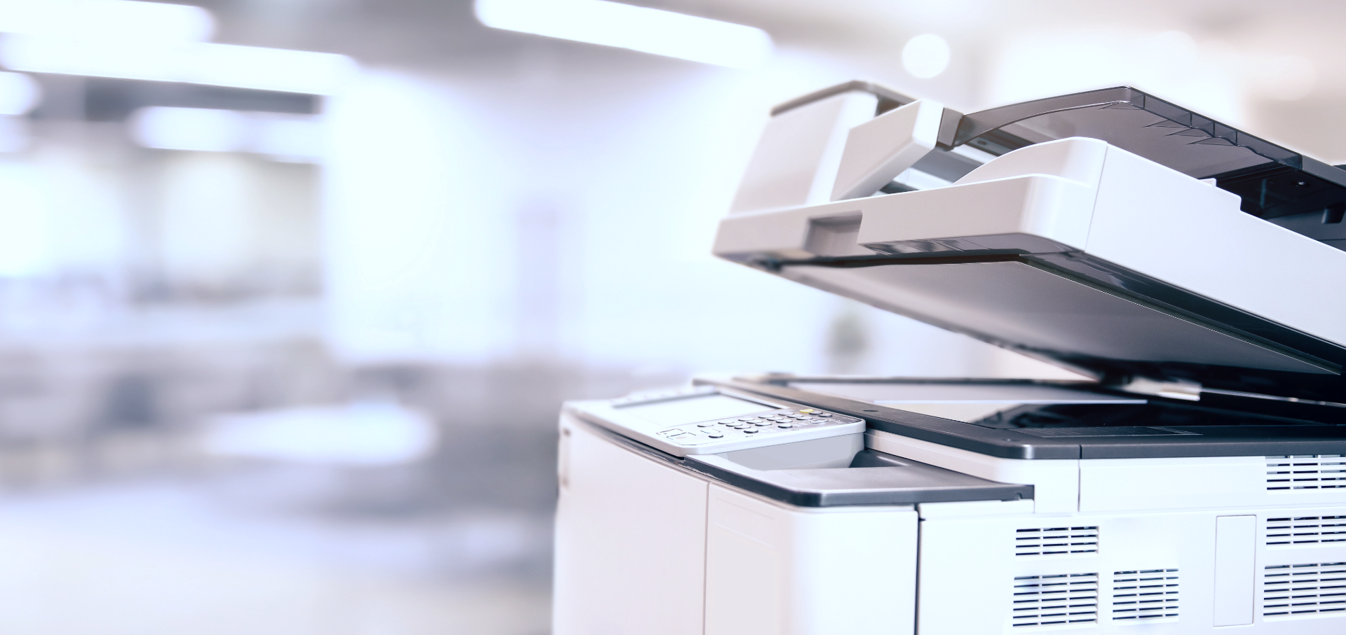 A close up of a printer in an office with the lid open.