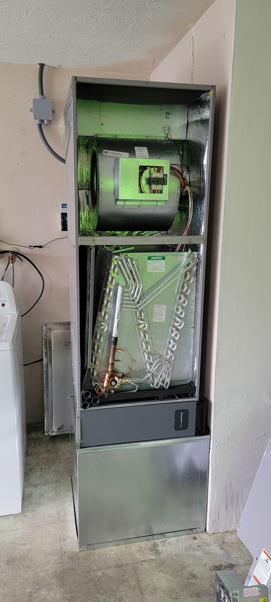 An air conditioner is sitting in a room next to a washer and dryer.