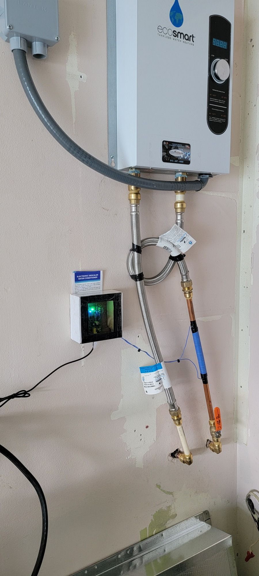 A water heater is hanging on a wall in a bathroom.