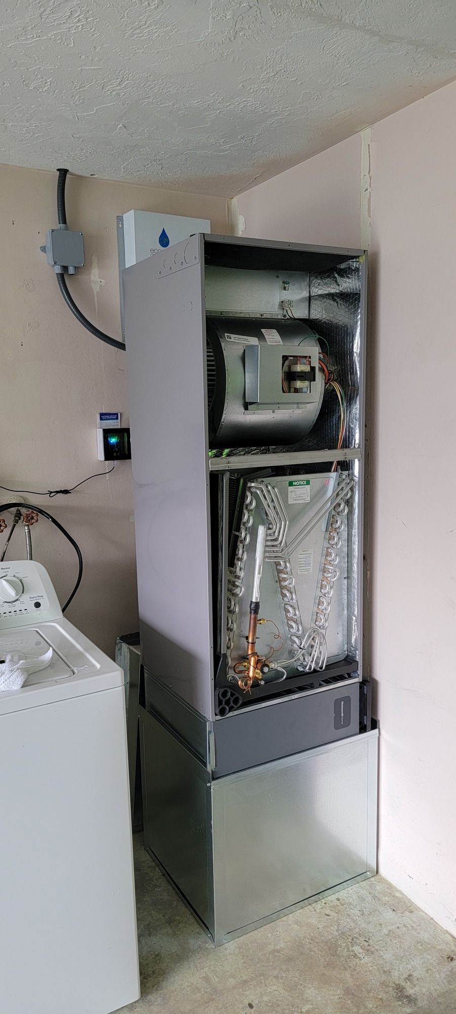 An air conditioner is sitting in a laundry room next to a washer and dryer.