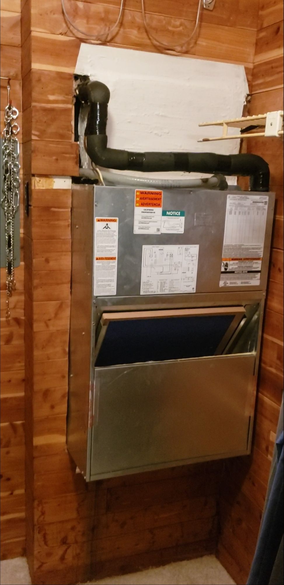 A stainless steel air conditioner is hanging on a wooden wall in a room.