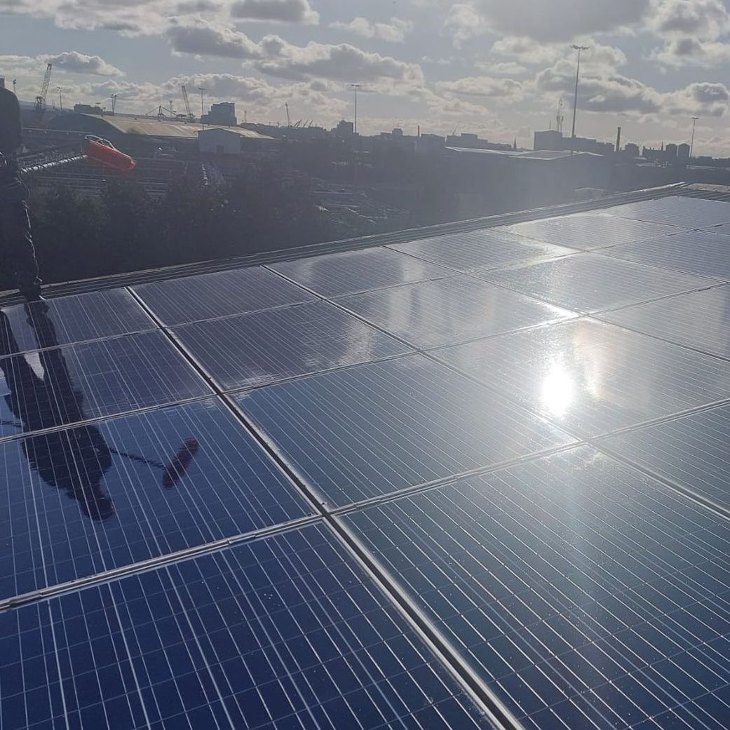 A row of solar panels on a roof with the sun shining through them