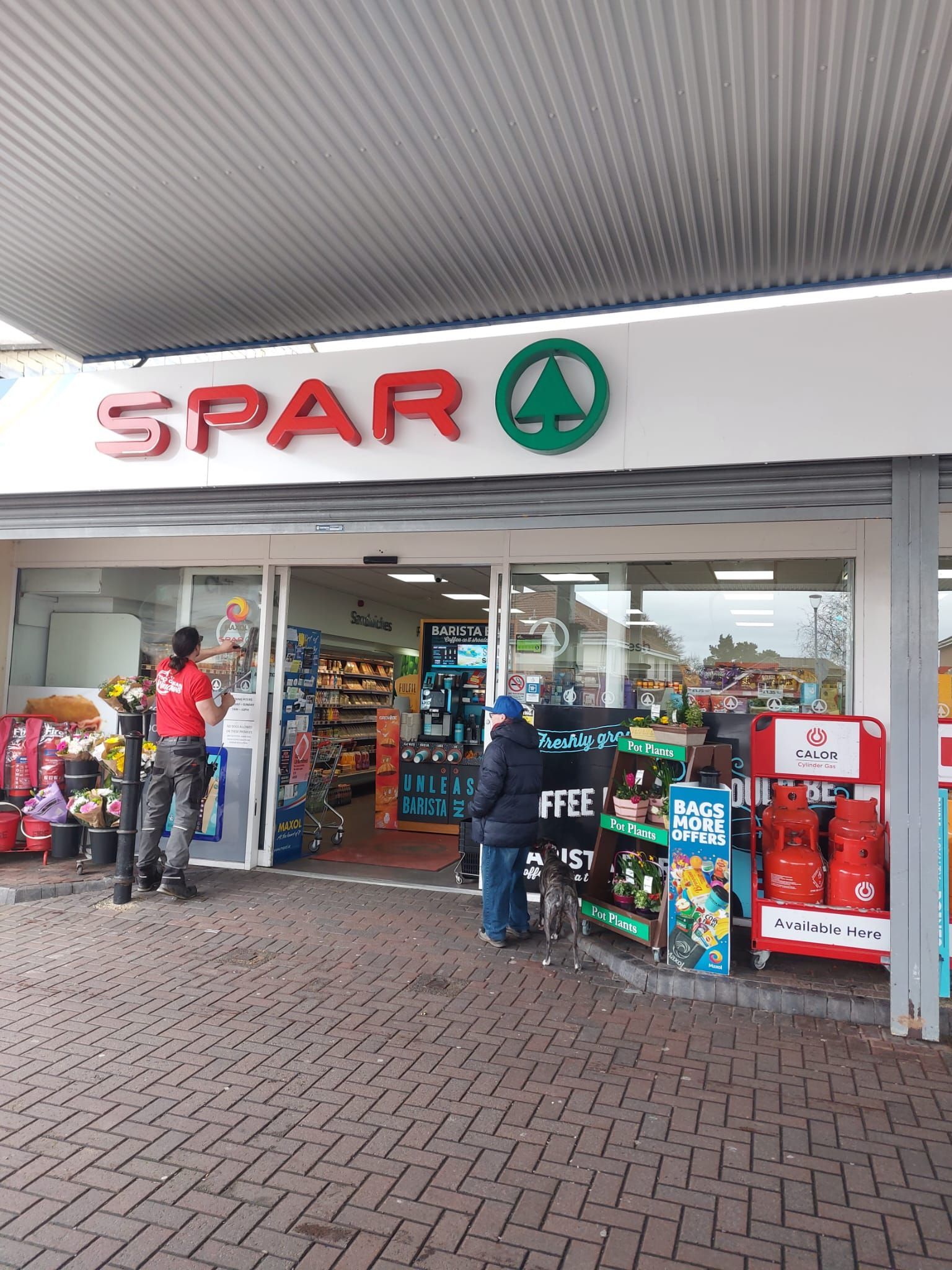 A group of people are standing outside of a spar store.