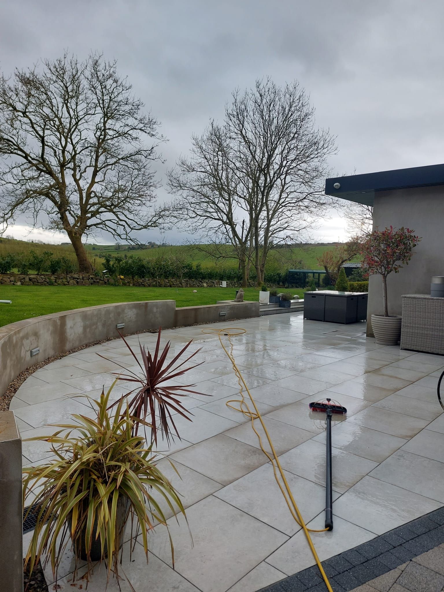 A patio with a broom and a potted plant on it.