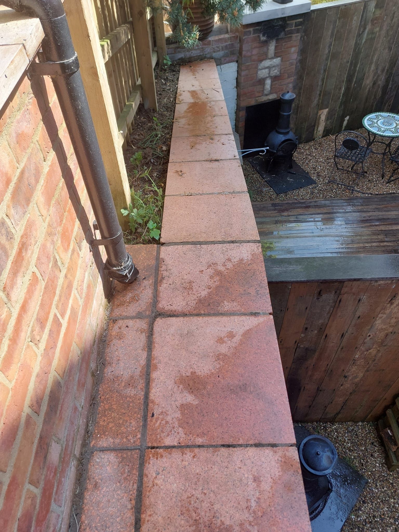 A brick walkway next to a brick wall and a wooden deck.