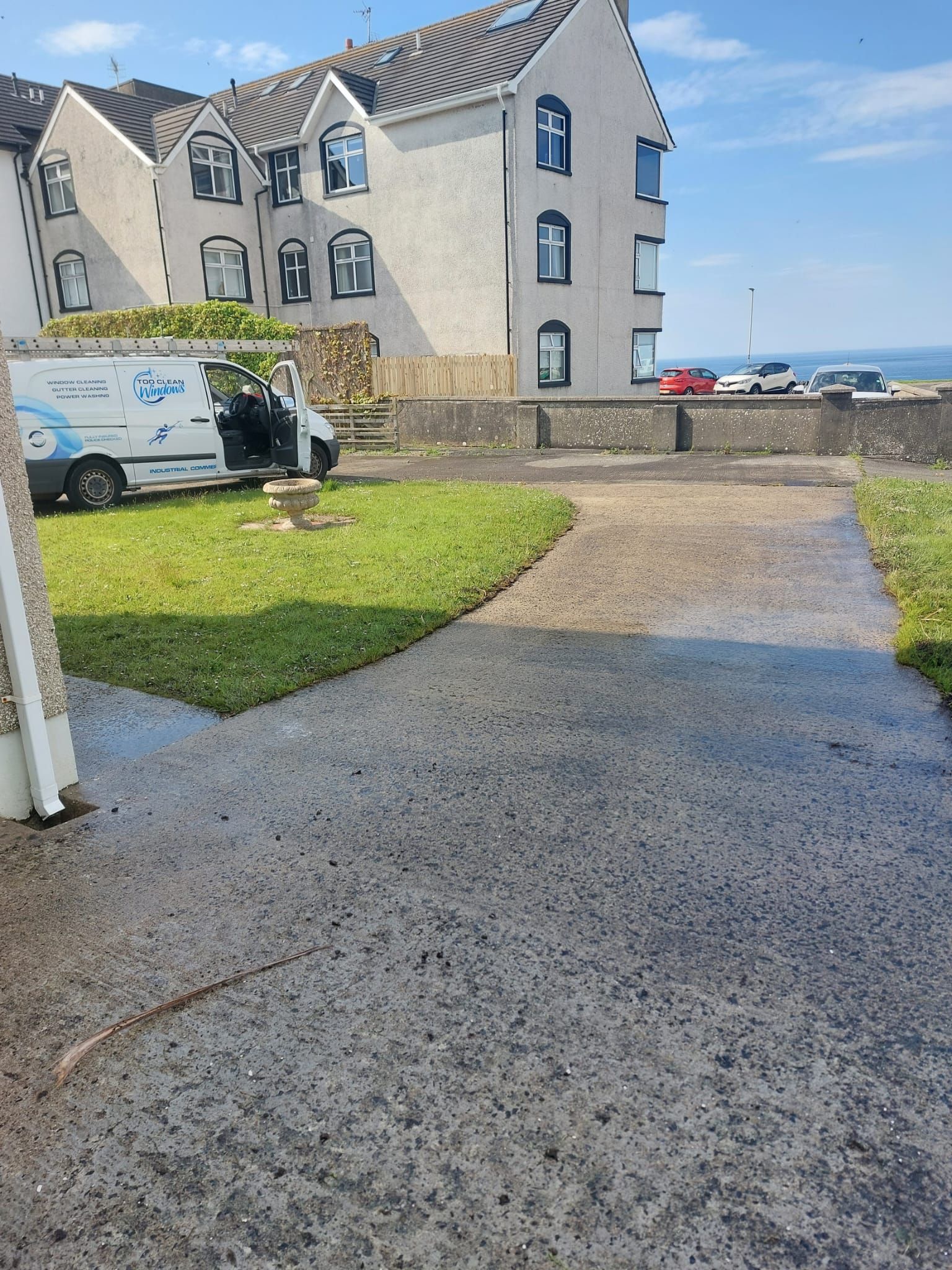 A white van is parked in front of a large building.