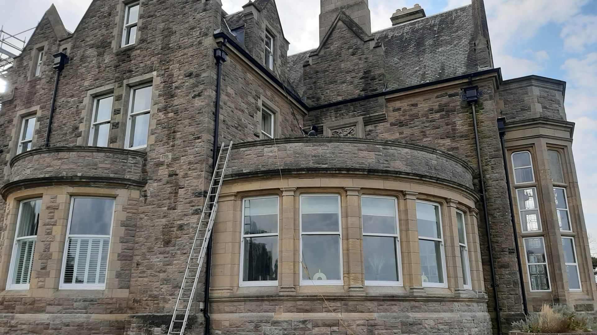 A large stone building with a ladder on the side of it.
