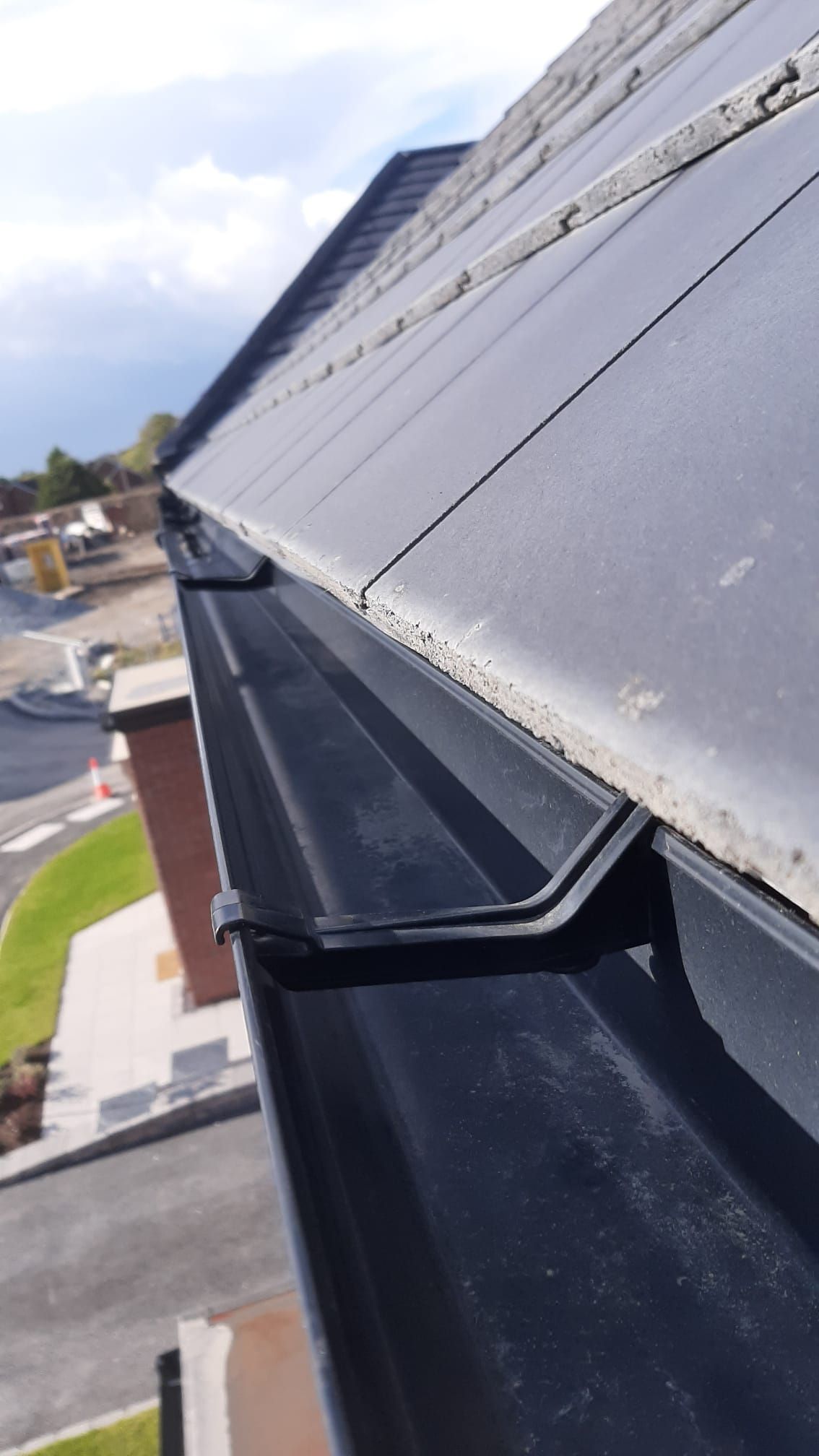 A black gutter is attached to the side of a roof.