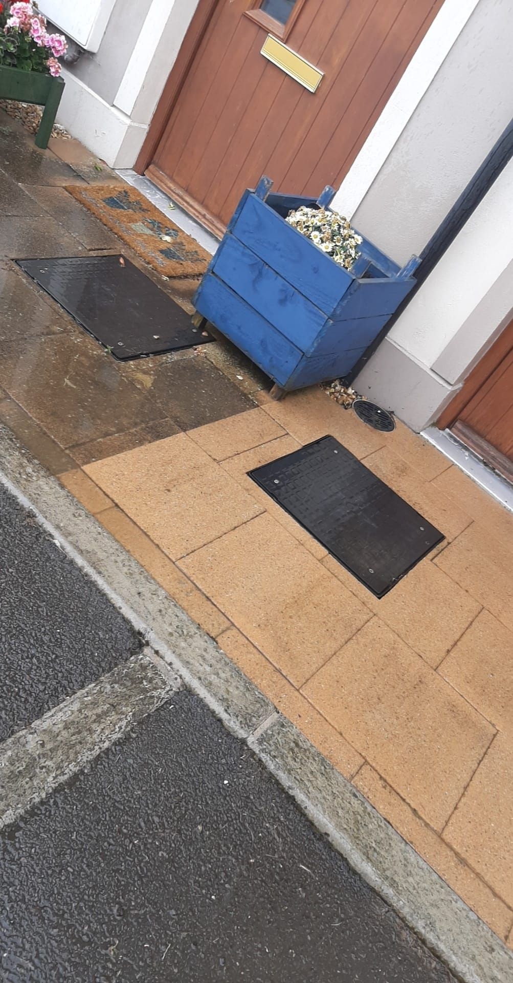 A blue planter is sitting on the sidewalk next to a door.