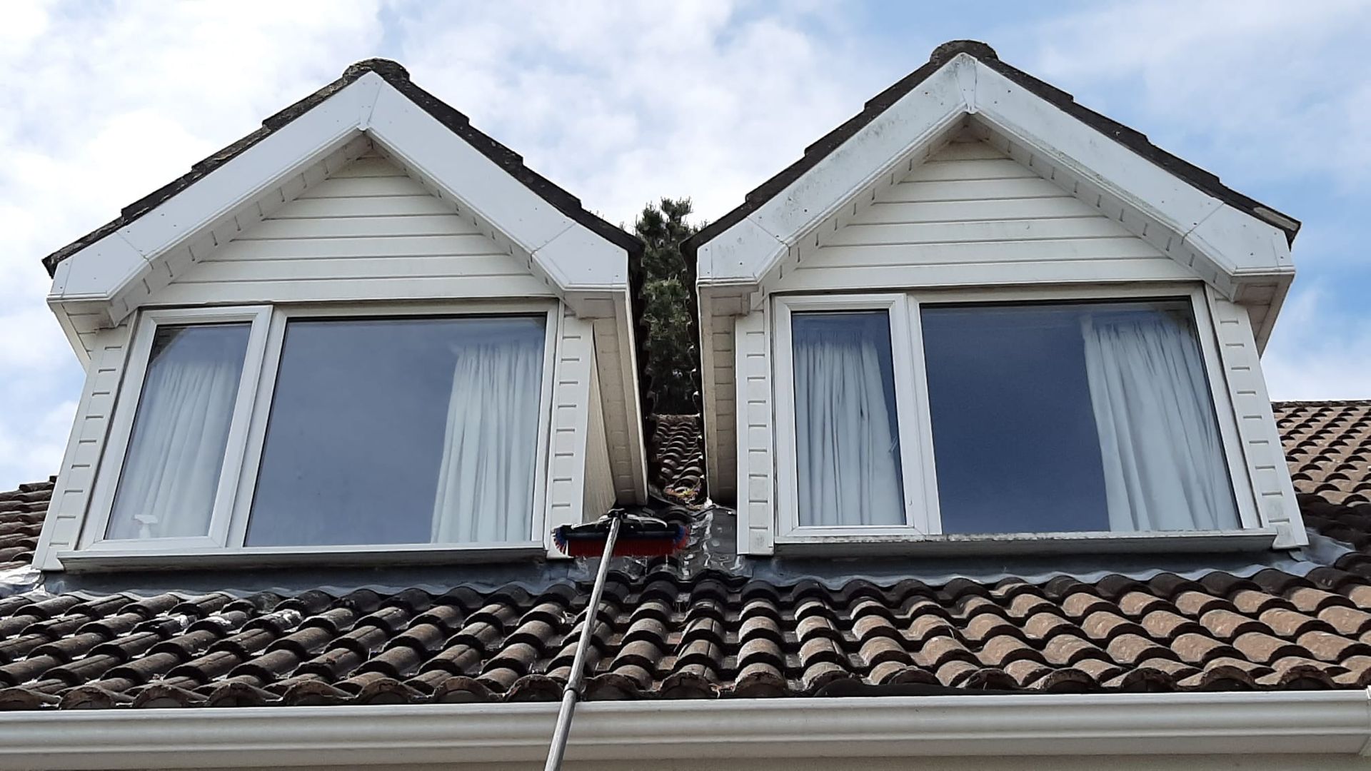 A person is cleaning the windows of a house with a hose.