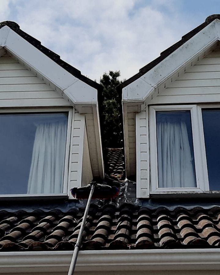 A person is cleaning the roof of a house with a broom.