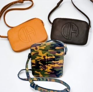 Three small, crossbody bags: orange, brown, and camouflage; each with a circular logo embossed on the front.