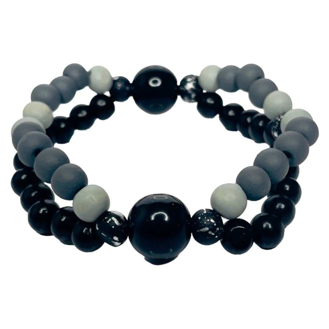 Two stacked beaded bracelets; black, gray, and white beads. Large black bead in the center of each bracelet.