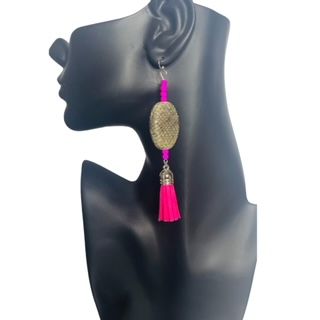 Hot pink tassel earrings on a black mannequin head.
